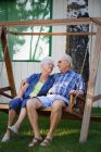 Seniorenpaar sitzt auf Schaukel und schaut sich an — Stockfoto