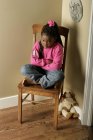 Menina triste sentada na cadeira no canto — Fotografia de Stock