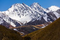 Picos de montaña cubiertos de nieve con colinas a pie durante el día - foto de stock