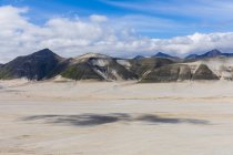 Vista del campo de arena con colinas rocosas bajo el cielo nublado en el fondo durante el día - foto de stock