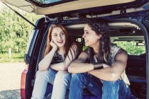 Two girls sitting at car while speaking with each other during daytime — Stock Photo