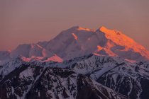 Snow covered peaks on mountains on sunset — Stock Photo