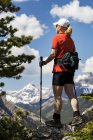 Escursionista femminile in piedi sulla cima della catena montuosa che domina la catena montuosa con nuvole e cielo blu; Banff, Alberta, Canada — Foto stock