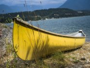 Barco de madeira amarelo ancorado na costa contra a água do lago durante o dia — Fotografia de Stock