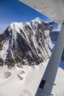 Vista del acantilado de montaña en la nieve y vista parcial de hilicopter contra pico - foto de stock