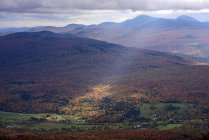 Un raggio di sole splende attraverso le nuvole per la foresta colorata autunno sottostante; Dunham, Quebec, Canada — Foto stock