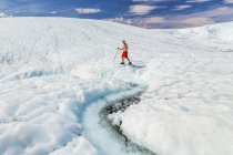 Uomo in pantaloncini rossi escursionismo su ghiaccio e neve sulle piste durante il giorno — Foto stock