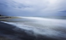 Acqua di mare tranquilla con un po 'di nebbia contro la riva sabbiosa durante il giorno — Foto stock