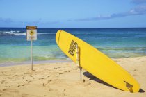 A bright yellow surfboard used for lifeguard rescue on Poipu Beach; Poipu, Kauai, Hawaii, United States of America — Stock Photo