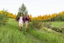 Счастливая пара бегает по зеленой траве на открытом воздухе в дневное время с рукой об руку — стоковое фото