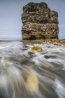 Вид на камінь над хвилястою водою моря вдень — стокове фото