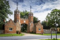 View of church with towers and arch entrance under cloudy sky, Melford Hall, Great Britain — Stock Photo