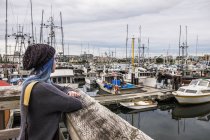 Mujer joven mira hacia fuera sobre Fisherman 's Wharf; Victoria, Columbia Británica, Canadá - foto de stock