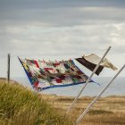 A patchwork blanket and pillow cases hanging on a clothesline with the Atlantic ocean in the background; Newfoundland, Canada — Stock Photo