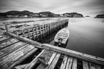 View of wooden dock with moored boat over water, balck and white picture — Stock Photo