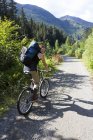 A Woman Mountain Bikes Down A Trail In A Forest With A Backpack; Alaska, United States Of America — Stock Photo
