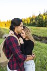 Junges verliebtes Paar steht auf Feld und umarmt sich mit Bäumen im Hintergrund — Stockfoto