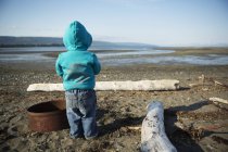Un jeune garçon se tient sur une plage regardant vers l'eau, Homer Spit ; Homer, Alaska, États-Unis d'Amérique — Photo de stock