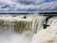 Великий водоспад з сильним водяним потоком на тлі похмурого неба вдень — стокове фото