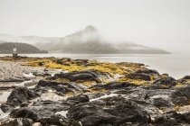 Vue du rivage rocheux contre l'eau de mer avec des collines sur le fond — Photo de stock