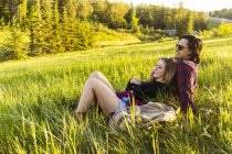 Романтична пара кладе на зелену траву над полем з деревами на фоні, обнімаючи один одного — стокове фото