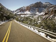 Highway road going through mountains snow covered peaks — Stock Photo