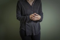 Imagen recortada de mujer casual con los dedos cruzados de pie contra la pared verde - foto de stock