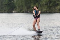 Una ragazza adolescente wakeboarding dietro una barca su un lago; Lago del Bosco, Ontario, Canada — Foto stock