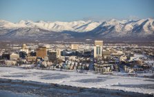 Vue aérienne de la neige recouvrant le centre-ville d'Anchorage et les montagnes Chugach au loin, Cook Inlet au premier plan, centre-sud de l'Alaska en hiver ; Anchorage, Alaska, États-Unis d'Amérique — Photo de stock