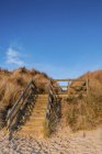Wooden steps leading into the dunes from the beach in warm sunlight at sunrise; Northumberland, England — Stock Photo