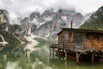 Casa de barco de madeira lago com neblina montanha nublada no fundo e reflexão lago; Sesto, Bolzano, Itália — Fotografia de Stock