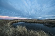 Pôr do sol sobre uma lagoa no Parque Nacional de Gramados; Saskatchewan, Canadá — Fotografia de Stock