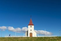 Chica caminando por la pequeña iglesia; Langaholt, Islandia - foto de stock