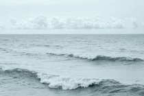 Wellen diagonal zum Bild und ein Band kleiner Kumuluswolken, die direkt über dem Horizont schweben; ontario, canada — Stockfoto