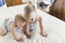 Two sisters playing together in bed at home — Stock Photo
