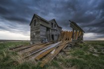 Abandoned house on the prairies with storm clouds overhead at sunset; Val Marie, Saskatchewan, Canada — Stock Photo