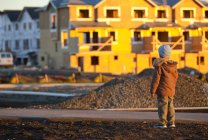 Rückansicht von boy standing and looking at new home construction in a neighborhood, langley, britisch columbia, canada — Stockfoto