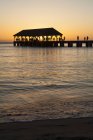 Sunset over ocean and silhouette of tourists on Hanalei Pier, Hanalei Bay; Hanalei, Kauai, Hawaii, United States of America — Stock Photo