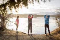 Three young women stretching on a trail at the water's edge; Anchorage, Alaska, United States of America — Stock Photo