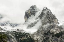 Pic montagneux accidenté avec un pic traversant la couverture nuageuse et la neige ; Grainau, Bavière, Allemagne — Photo de stock