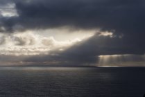 La luz del sol atraviesa las nubes frente a la costa de Oregon; Manzanita, Oregon, Estados Unidos de América - foto de stock