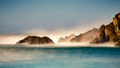 Nebbia sopra l'acqua turchese lungo la costa frastagliata; Big Sur, California, Stati Uniti d'America — Foto stock