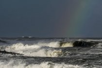Temps orageux apporte drame au ciel sur la côte de l'Oregon avec un arc-en-ciel de couleur contre le nuage sombre au-dessus des vagues ; Bord de mer, Oregon, États-Unis d'Amérique — Photo de stock