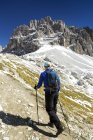 Randonneuse sur un sentier escarpé avec des sommets montagneux accidentés et un ciel bleu en arrière-plan, Sesto, Bolzano, Italie — Photo de stock