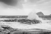 Black and white image of waves splashing against rocks at the shore along the coast of Norway — Stock Photo