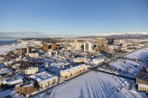 Вид с воздуха на снежный покров в центре Анкориджа и горы Чугач и Талкитна, простирающийся вдалеке за городом, Парк Сектор виден на переднем плане, Юго-Центральная Аляска зимой; Анкоридж, Аляска — стоковое фото