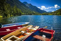 Colourful row boats with Champex Lake surrounded by mountains under blue sky, Alps; Champex, Switzerland — Stock Photo