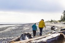 Ein älteres paar wandert mit wanderstöcken am strand entlang der küste, wiesennebel campingplatz, graham island; tlell, haida gwaii, britisch columbia, canada — Stockfoto