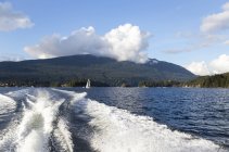 Оглядываясь назад на горный хребет и город, когда лодка направляется дальше в Глубокую бухту и парк в Индиан Армс, популярная однодневная поездка для жителей Ванкувера и туристов; Ванкувер, Британская Колумбия, Канада — стоковое фото