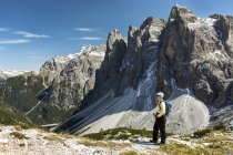 Female hiker overlooking valley against rugged mountain range and blue sky, Sesto, Bolzano, Italy — Stock Photo